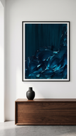 A framed abstract art print featuring deep blue and black fluid brushstrokes, displayed on a white wall above a wooden console table with a small black vase.