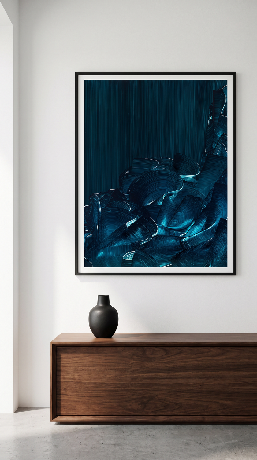 A framed abstract art print featuring deep blue and black fluid brushstrokes, displayed on a white wall above a wooden console table with a small black vase.