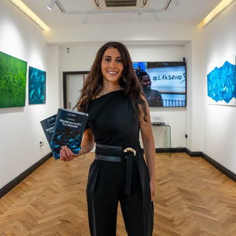 Lara Sayegh, contemporary abstract artist, at her exhibition in London surrounded by fluid movement abstract paintings